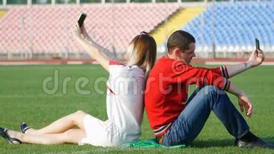 年轻人和美女坐在足球场上自拍